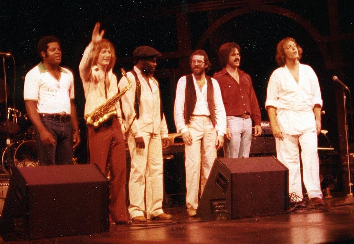 The band Augustwolf, seven musicians in white and red stage clothes, taking a bow after a show
